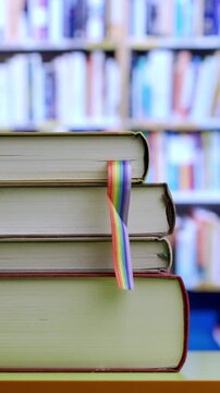 Books.Table and person hands leave with rainbow flag books at library.