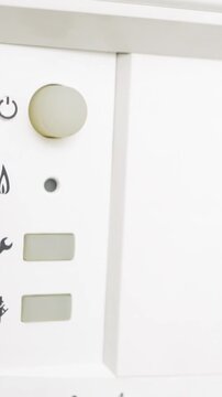 Switching on the home boiler. The beginning of the heating season. The man's hand turns on the boiler and sets the temperature of heating and hot water