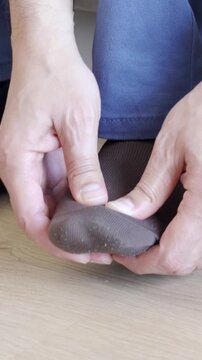 Close-up of man touching feet with his hand at office