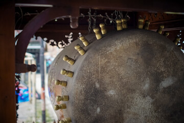 Fototapeta premium Close-up low angle view of a large traditional Bedug drum, highlighting brass pegs and weathered drumhead texture. Cultural Islamic percussion instrument in ornate wooden pavilion