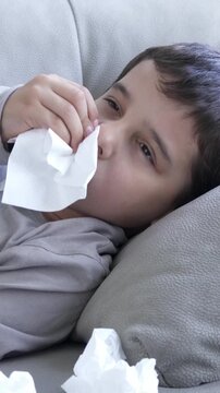 My nose wont stop dripping. Shot of a child feeling ill in couch at home and blowing his nose.