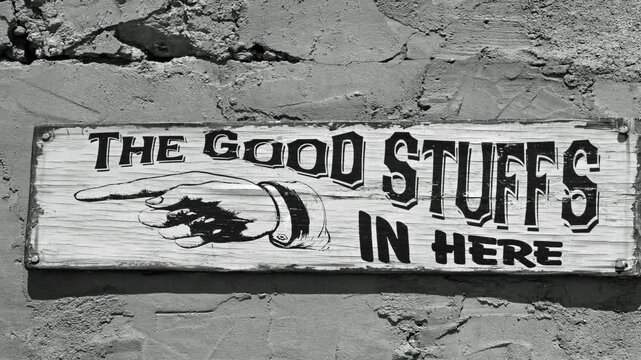 Old style black and white movie of a Ghost town sign. The Good stuffs in here 