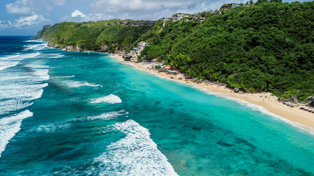 Drone view of turquoise beach and rolling waves along tropical shore