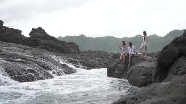 Friends Watching Ocean Water Flow Through Rocky Tide Pool