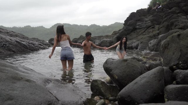 Friends Holding Hands in Coastal Tide Pool Adventure Indonesia
