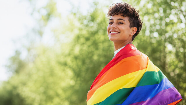 Smiling person pride flag lgbt rainbow color outdoor happy young adult queer identity freedom confidence celebration summer nature green background community equality diversity inclusion support