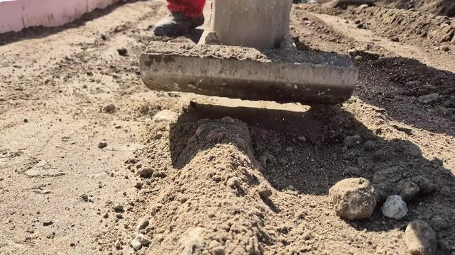 Front view slow motion shot of soil compaction, showing the powerful impact and movement of a handheld rammer compactor.