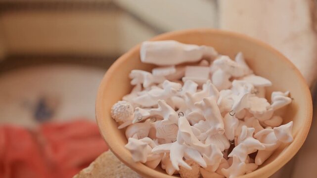Closeup pottery bowl filled with bisque shards, clay fragments and frit in warm workshop setting, wooden table and floral tile background, soft natural light, textured detail for craft and studio