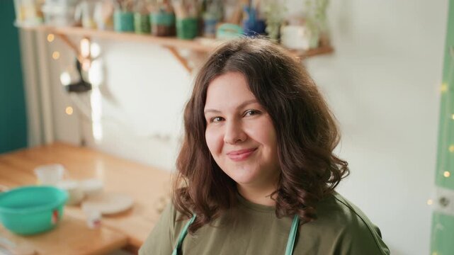 Latina potter in pottery workshop preparing orders and products at bench with bowls, jars and tools upbeat maker energy, apron and natural light emphasize entrepreneurship, packaging and studio