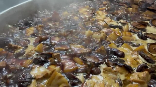 Close-up of braised pork belly boiling and simmering in an industrial cooking kettle. Food production process creating rich flavor and tender texture for commercial food manufacturing.