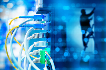 Network infrastructure, cable installation. Technician works in server room while Ethernet and...