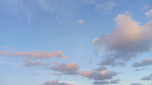 Beautiful blue sky background with soft pink pastel clouds during sunset golden hour