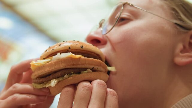 Closeup white woman taking big bite, food blogger persona with oversized sesame burger and fried egg, enthusiastic expression, hands gripping bun, bright mall interior, casual craving shot