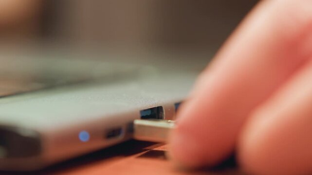 Close view of USB being connected. Office employee inserts flash drive into computer port with light. Person carefully plugs flash drive into computer port while indicator light glows