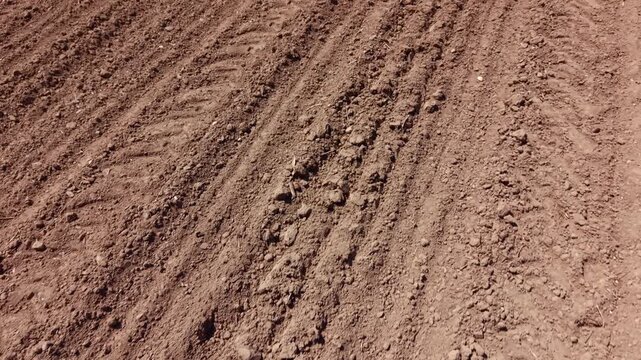 High angle aerial survey of spring agriculture field work. Drone clip of soil cultivation using a power harrow on an empty agricultural field.
