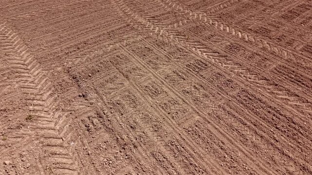 High angle view of a brown agricultural field from a drone. Flying over cultivated land with a distinct soil surface texture in late spring.