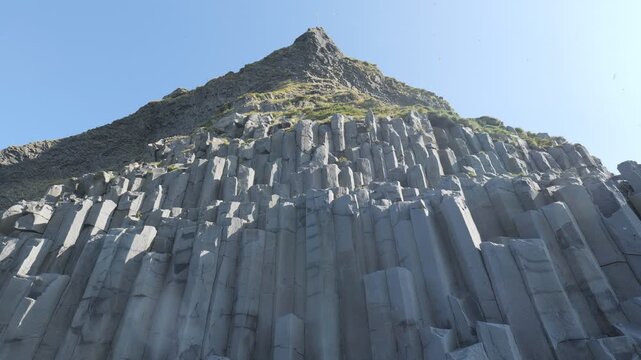 A steep cliff face made of dramatic, vertical basalt columns.