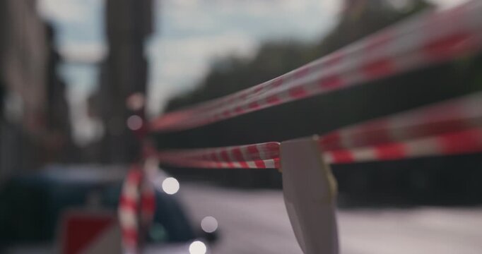 Red and white barrier tape stretched along a city street on a sunny day during Labor Day holiday.