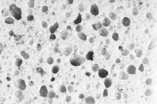Macro, closeup of white foam sponge texture with porous, spongy and bubbly surface pattern suitable for abstract background design. Foamed polyurethane material surface