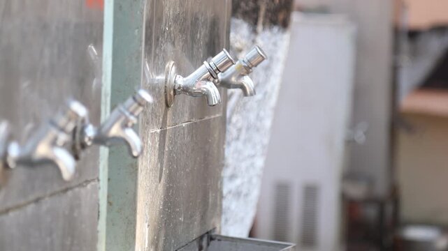 Raw video footage of stainless steel water taps installed at a Hindu temple for drinking water and hand washing after free community meals in rural India temple premises.