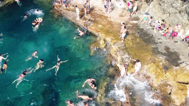 Stunning aerial perspective of Capri Faro beach with bathers enjoying clear Mediterranean waters