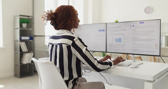 Analyst woman at computer in office reviewing analytics. Operator checks a dashboard to compile reports and deliver support during client consultation. Clear concept of finance data analysis.