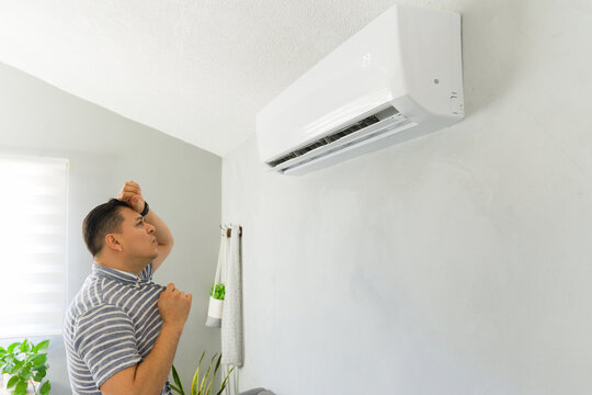 Frustrated man feeling hot during summer heatwave suffering from a broken or inefficient air conditioner