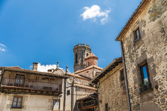 Church tower rising above medieval stone houses in Rupit village, Catalonia, Spain