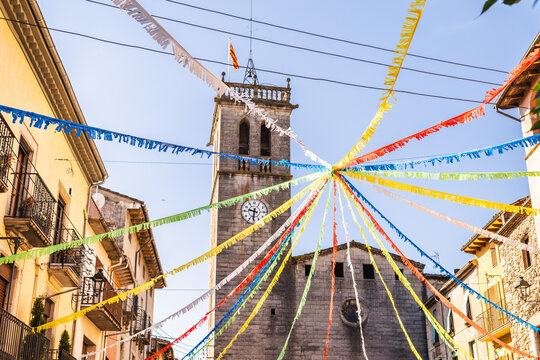 Colorful festival decorations leading to historic church in Catalan Sant Feliu de Palleros village square