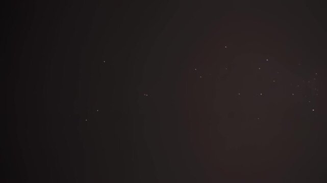 Bright golden light streak moving across a dark screen with glowing particles scattering in motion in this high quality abstract digital animation clip for creative visual design and artistic projects