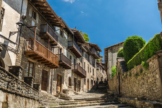 Medieval stone street with wooden balconies in Rupit village, Catalonia, Spain, featuring historic architecture