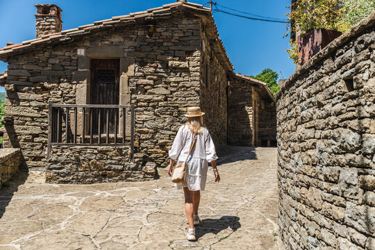 Woman exploring medieval stone village streets in Rupit, Catalonia, Spain, walking through historic old town with traditional architecture