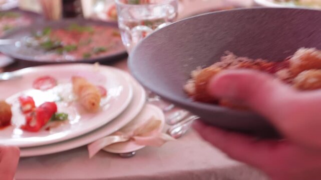 Close up of a waiter hand serving fried cheese balls topped with grated parmesan in a restaurant