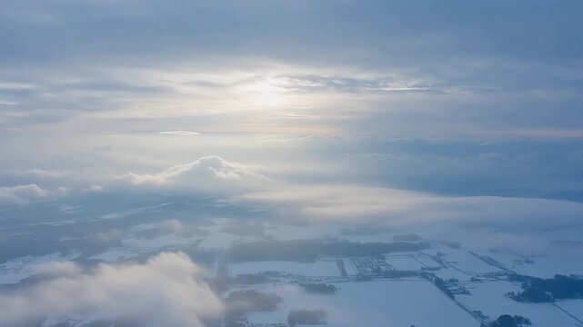 Aerial View of Snowy Landscape with Sunlight Breaking Through Clouds