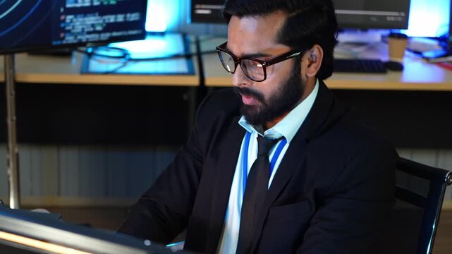 Indian software developer take off eye glass to look at computer monitor showing AI coding. Professional engineer review program script data on screen. Tech expert analyze deep learning network