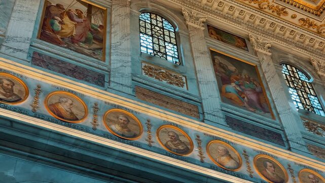A stunning interior view of the Basilica of Saint Paul Outside the Walls in Rome, Italy, featuring rows of majestic marble columns and a magnificent gilded coffered ceiling.

