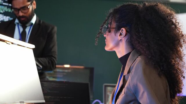 Female programmer listen to manager brief AI coding project on screen. Woman software developer attend business meeting to review program script. Tech employee work with team during presentation