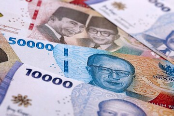 Indonesian rupiah money bills pile on table. Indonesia banknotes of IDR currency close up. © Larysa
