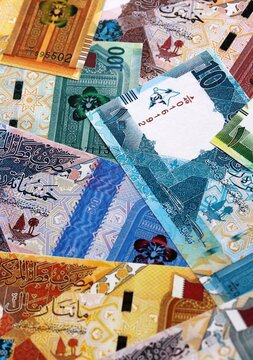 Qatari riyal money bills pile on table. Qatar banknotes of QAR currency close up.