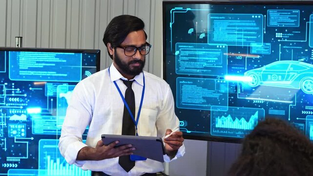 Indian developer holding tablet pointing pen at car engineering blueprint screen during innovative vehicle technology project presentation in office