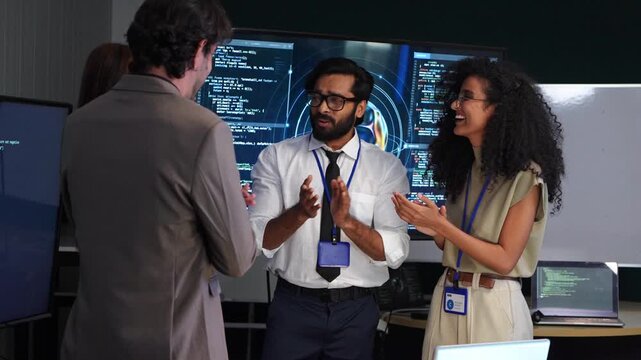 Happy tech team business colleague clapping hand and handshaking to celebrate success after software engineer code presentation to corporate manager at computer screen office workspace.