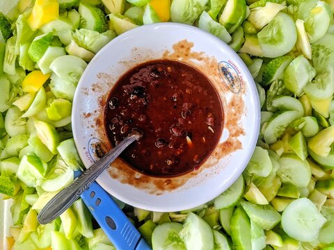 Indonesian traditional fruit salad rujak with spicy brown sugar peanut sauce and sliced fresh cucumbers