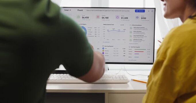 Couple budget planning finance on computer dashboard. They review a home finance screen, point with pen, compare expenses and savings, adjust goals. Clear concept of household money management