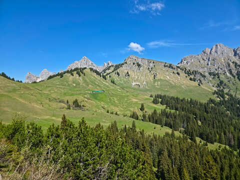 Austria, Rugged alpine rock landscape above lush valleys featuring traditional mountain hut and summer tranquility