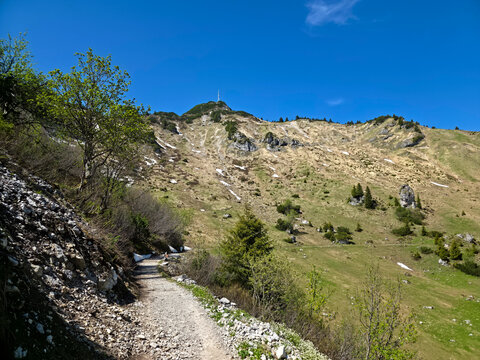 Austria, Towering alpine rock formations above verdant valleys crossed by scenic hiking trails and forests on hahnenkamm mountain trail