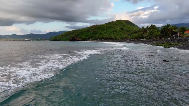Aerial of waves approaching a black sand beach in Bali Indonesia.