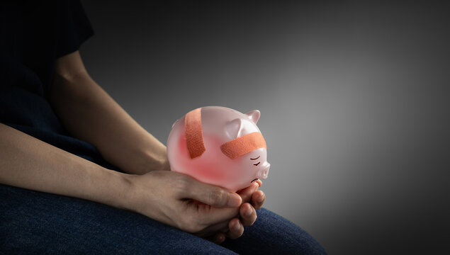 Person holding damaged piggy bank with bandage, Financial hardship