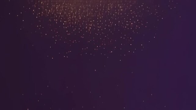 Golden light particles floating upward in a dark void create a magical atmosphere for this motion video clip with soft glowing embers rising slowly against a deep purple background texture