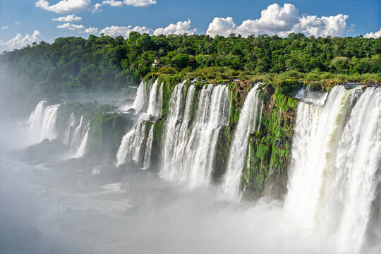 Panoramic view of the majestic Iguazu Falls in Iguazu National Park, a natural wonder of the world with powerful water cascades and lush green jungle under a blue sky