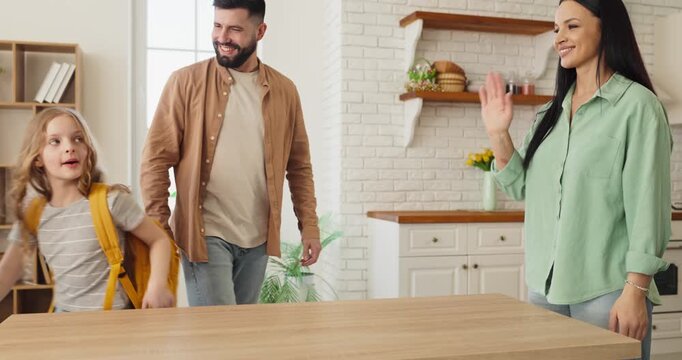 Family parents prepare girl for school morning routine. Parents wave goodbye as their daughter leaves with a backpack, showing support at home. Back to school family morning routine concept.